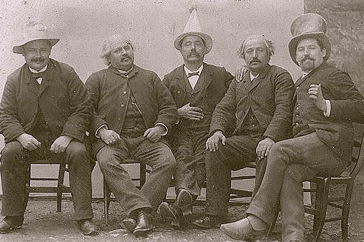 Old Photo From the 1800s Sepia of 5 sitting men on of the men has a funny pointed hat