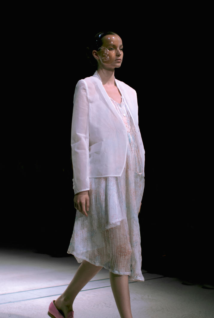 Anrealage Spring 2012 Fashion Artist Danny Roberts Photo of the profile of a model walking in a white body suit like Anrealage a white transparent coat with a white transparent with little print dress with a bubble mask in the Collection from Tokyo Fashion Week 2012