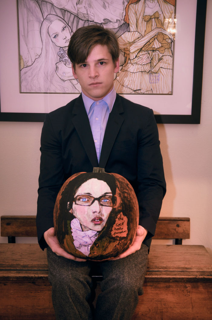 A portrait of Danny Roberts holding a pumpkin he painted of Model Coco Rocha